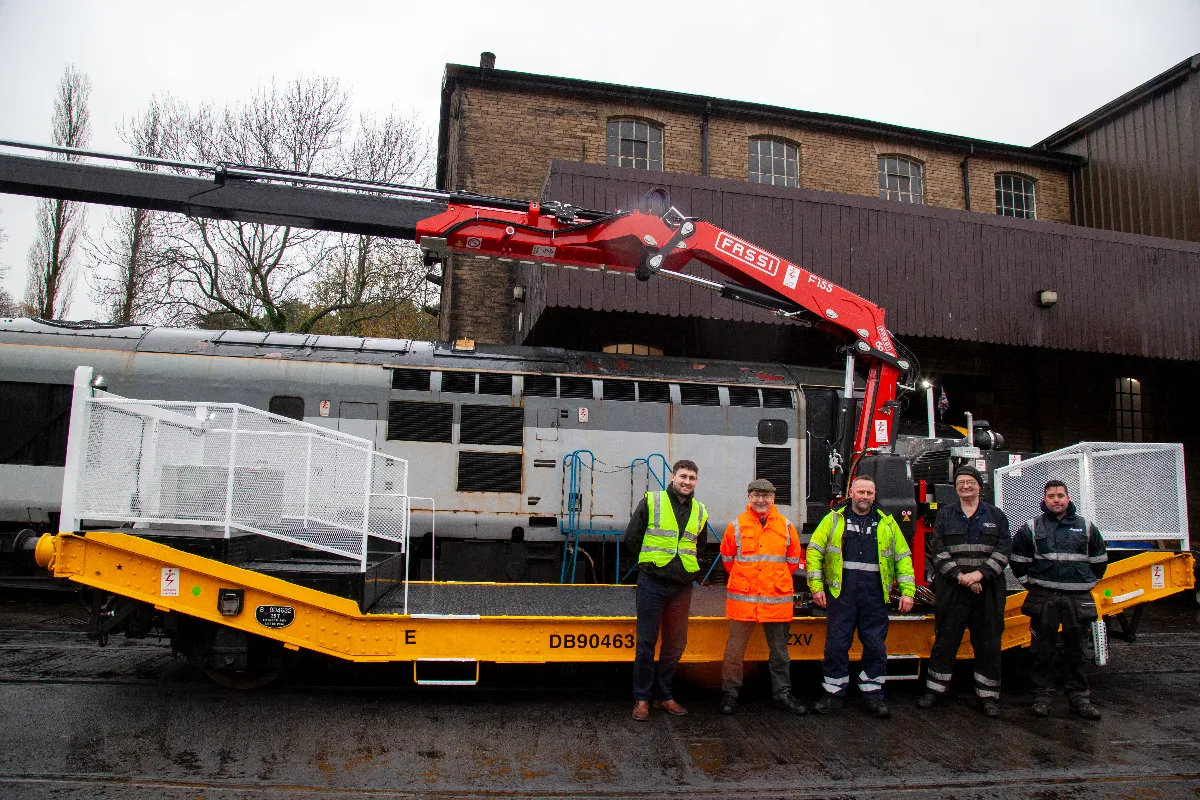 Mac's truck sales staff pose with members of the KWVR team in front of a FASSI railway wagon